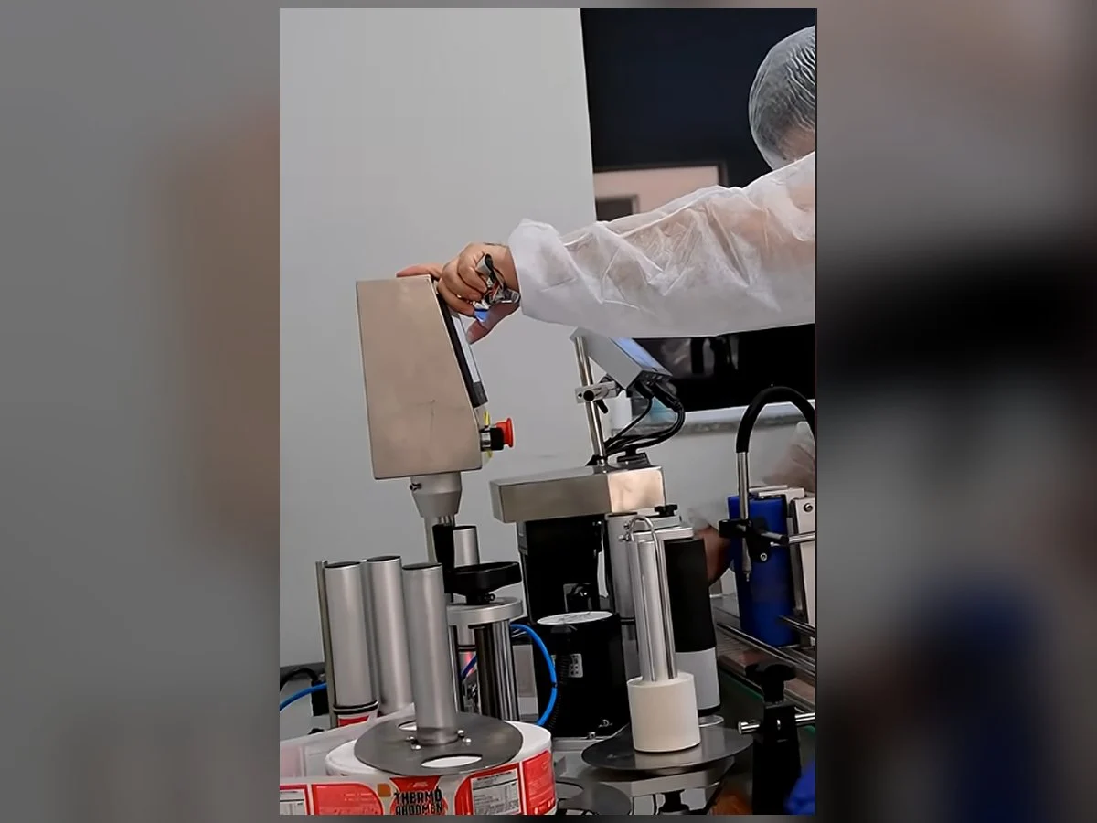 Operador ajustando rotuladora automática ABEMAG TSI em linha de produção